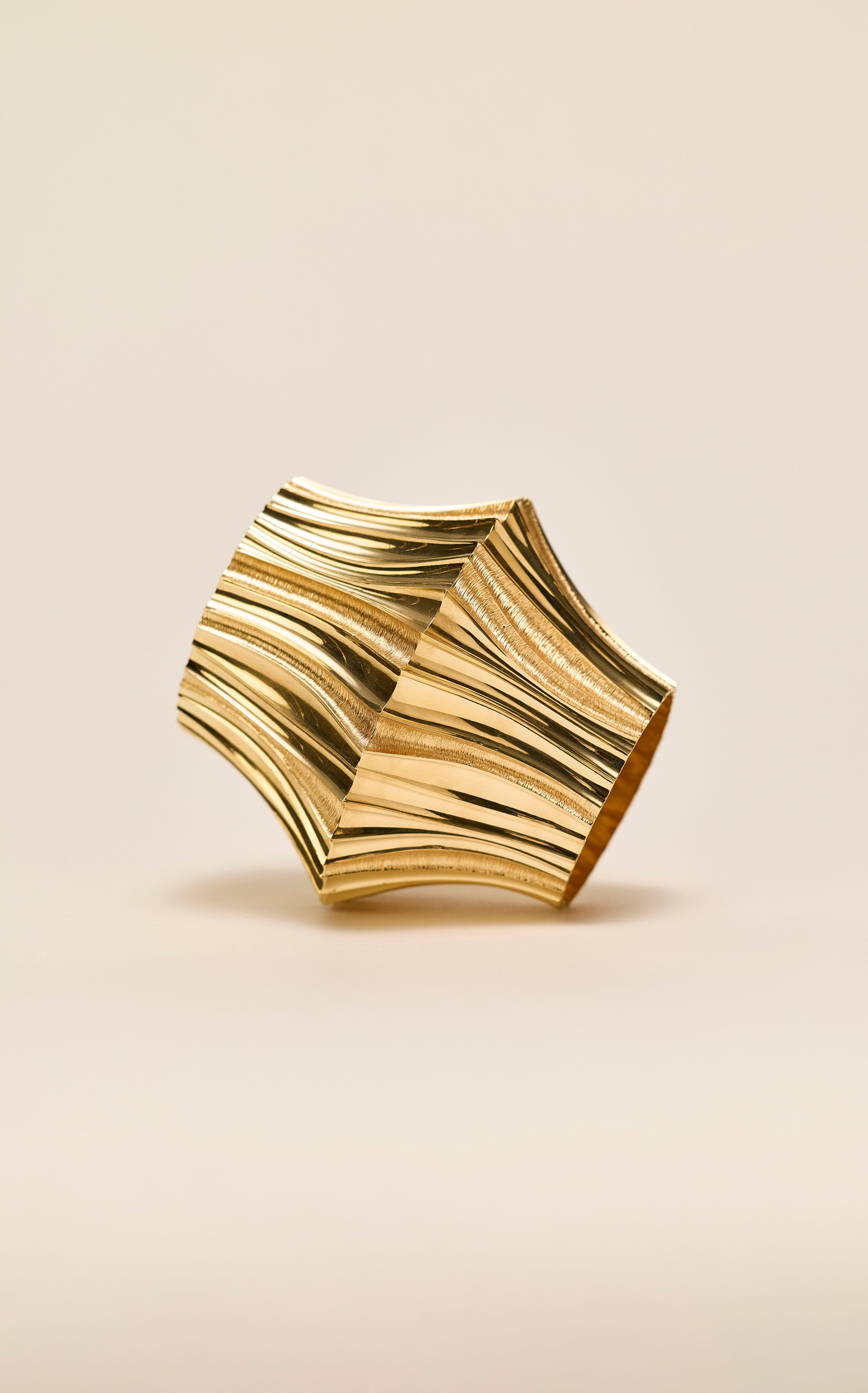 Coriolis Bangle sculpted in bronze with continuous circular textured form, finished in 24k gold plating